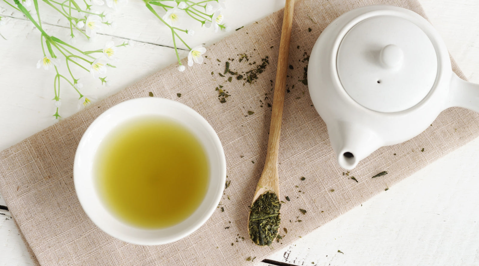 A cup of tea sits next to a tea pot