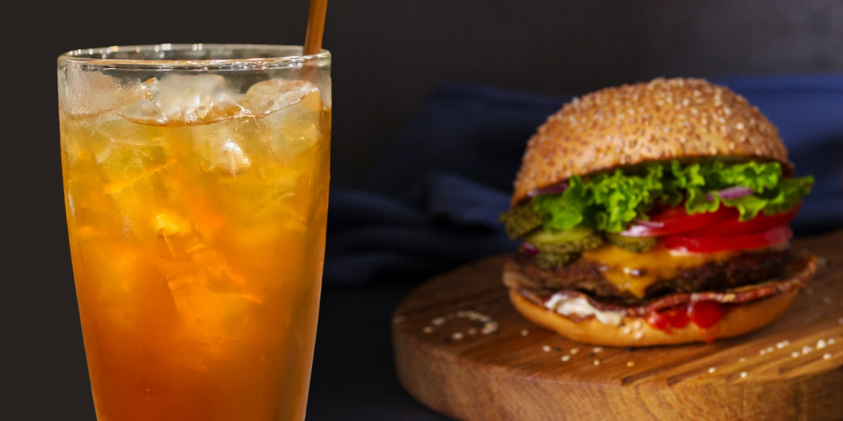 Glass of iced tea next to a burger