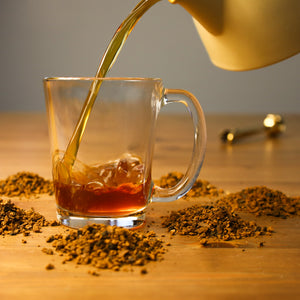 Chaga tea being poured into glass cup.
