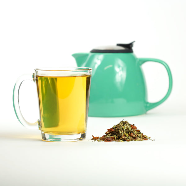 Glass of brewed Mindmender tea next to mound of Mindmender loose leaf tea.