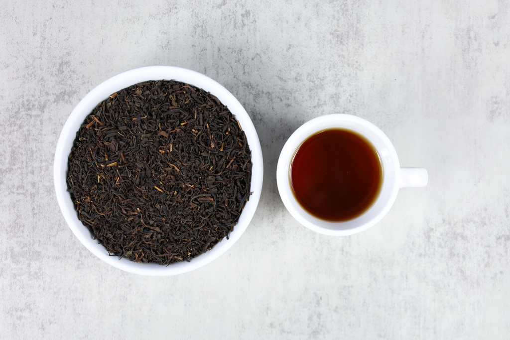 A cup of brewed organic Wakoucha next to a bowl of loose tea leaves