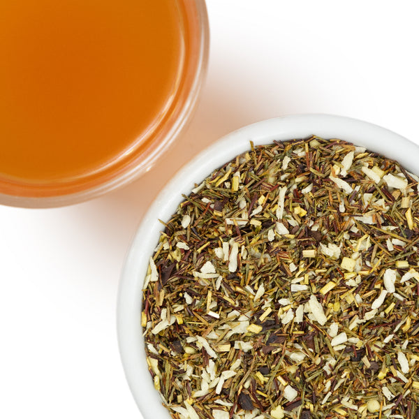 A topdown view of loose leaf tea next to a cup of brewed tea