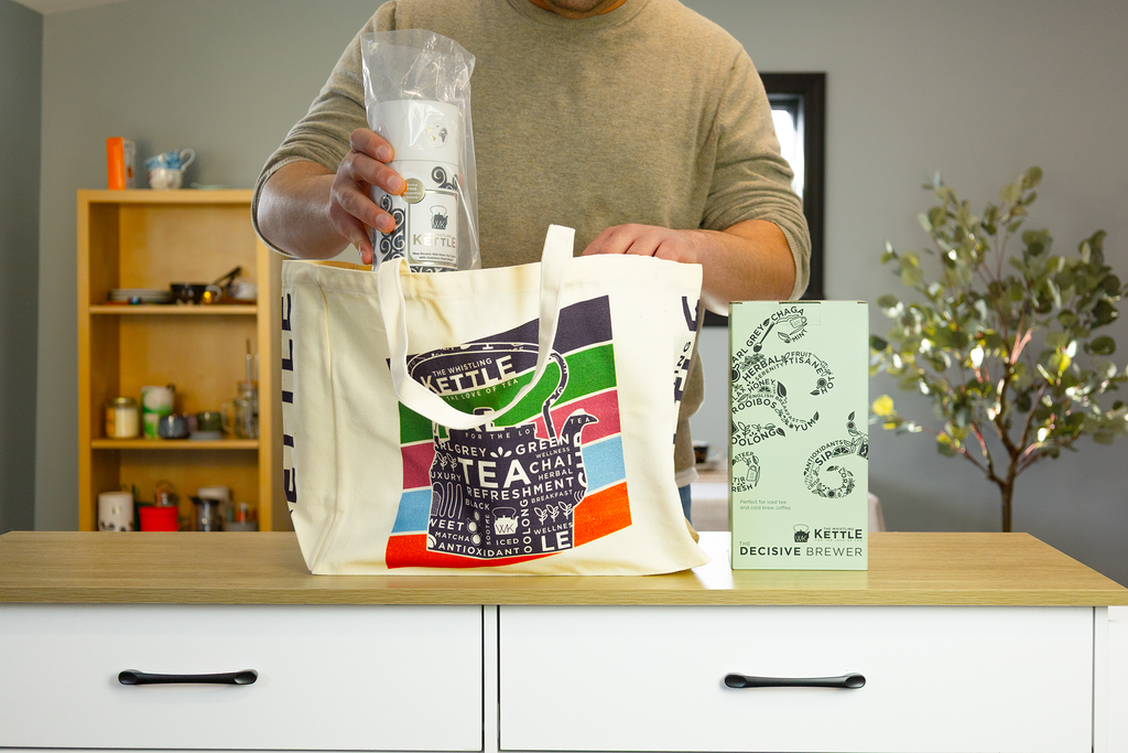 A man places items into a Whistling Kettle tote bag