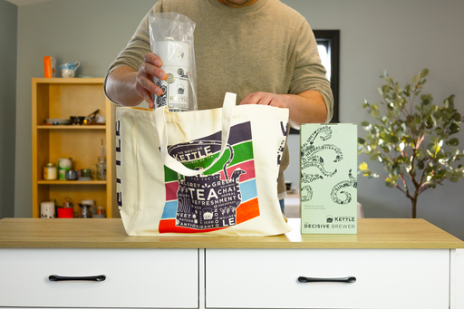 A man places items into a Whistling Kettle tote bag