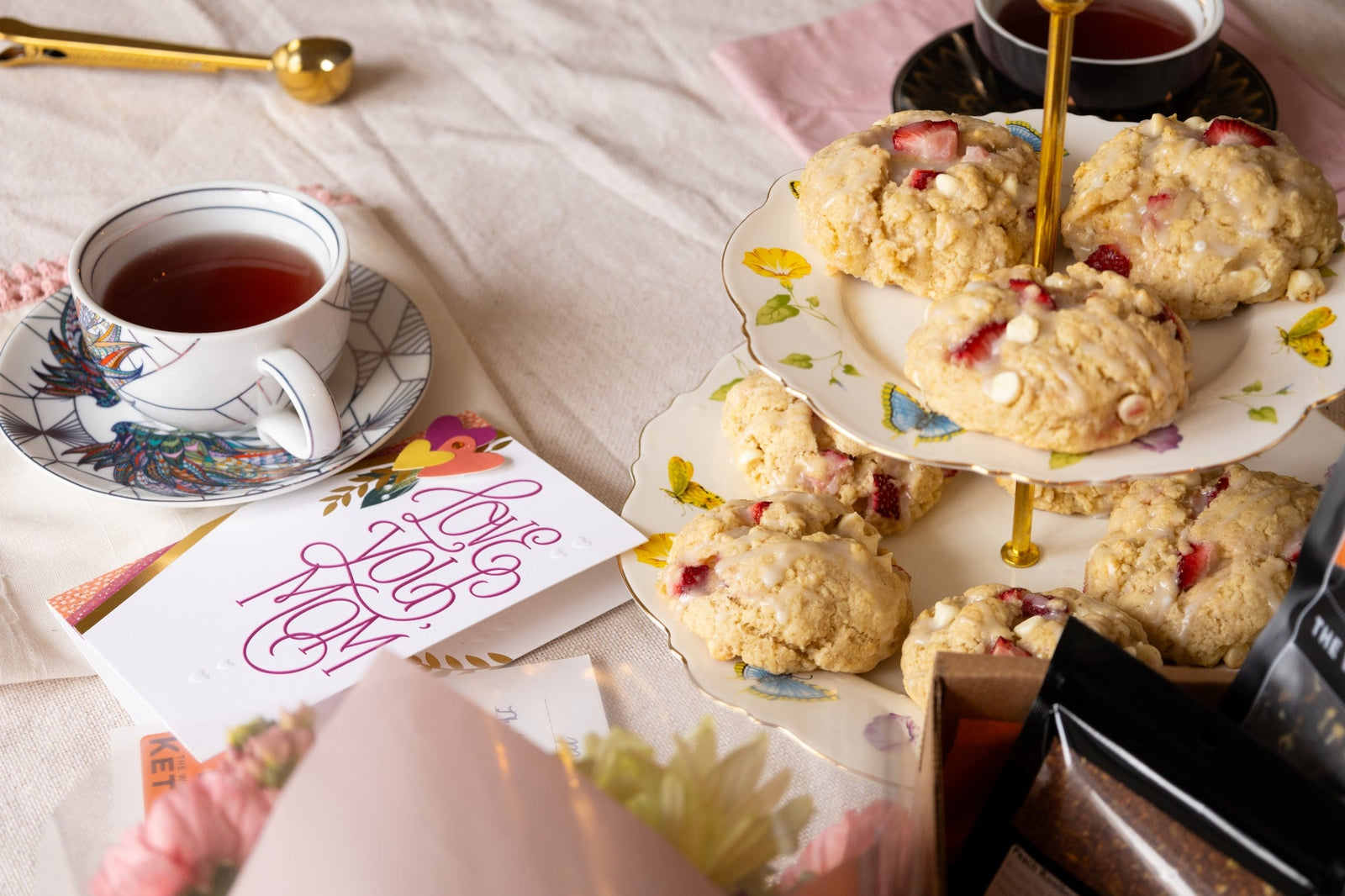 strawberries and cream scones on a tray next to a mother's day card and a cup and saucer filled with tea