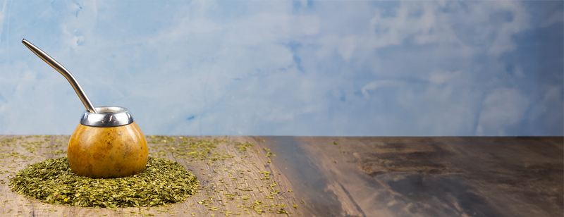 A calabash gourd sits on a pile of yerba mate