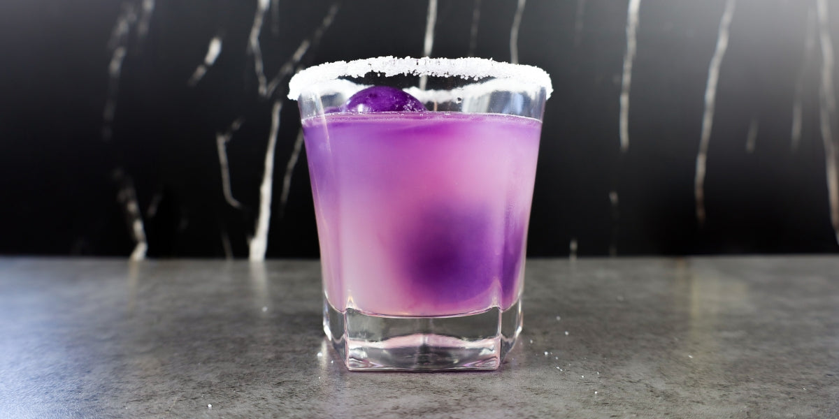 Lemon drop cocktail in a rocks glass with purple papayaberry tea ice cubes