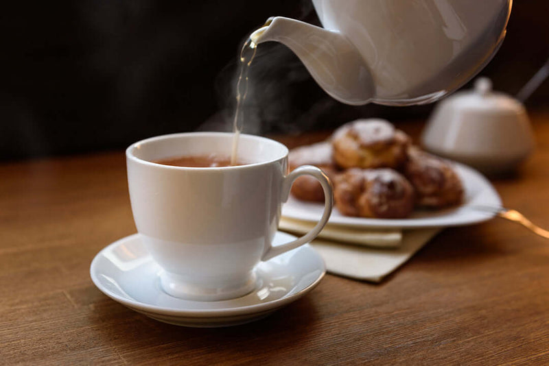 English Breakfast tea being poured into a tea cup.