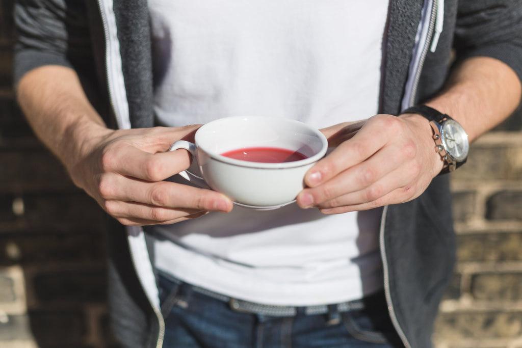A man holds a cup of hibiscus tea