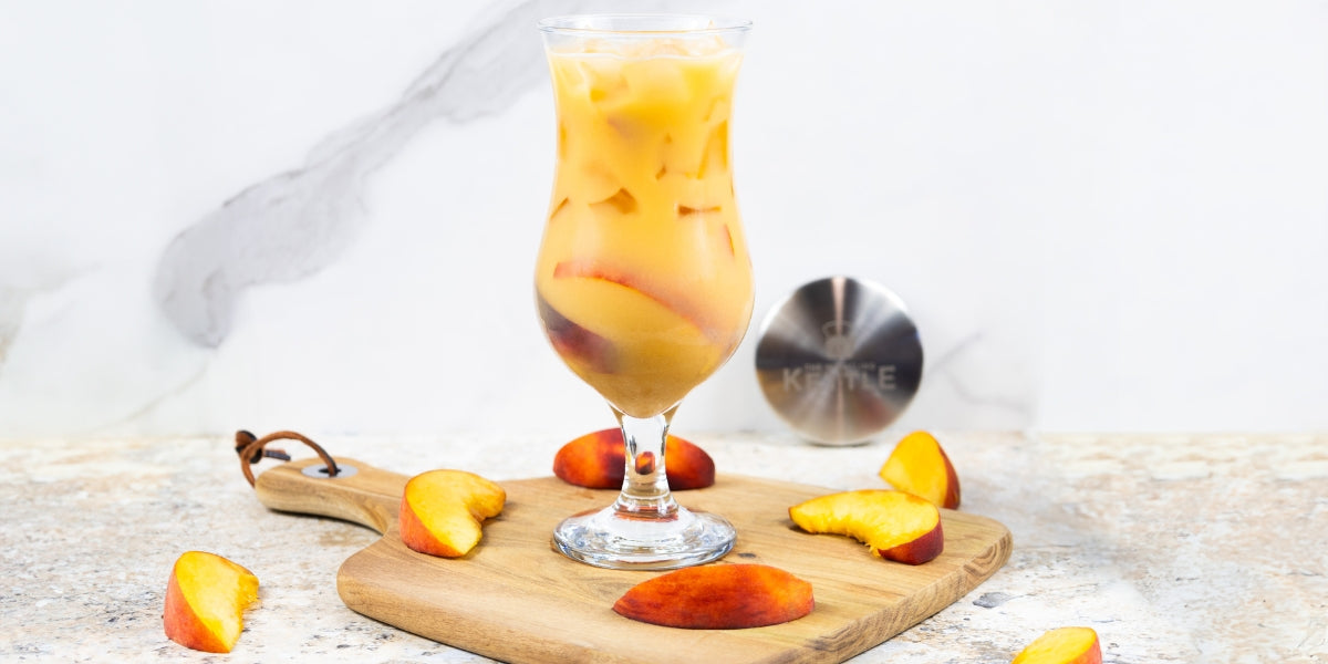 Peaches and Cream Latte on a cutting board with fresh peach slices
