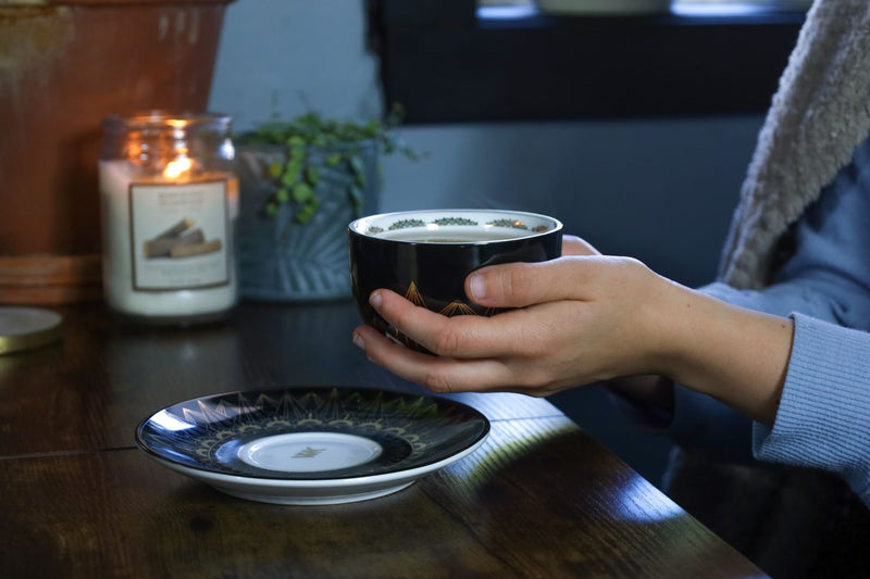 Holding a black and gold cup with tea in it