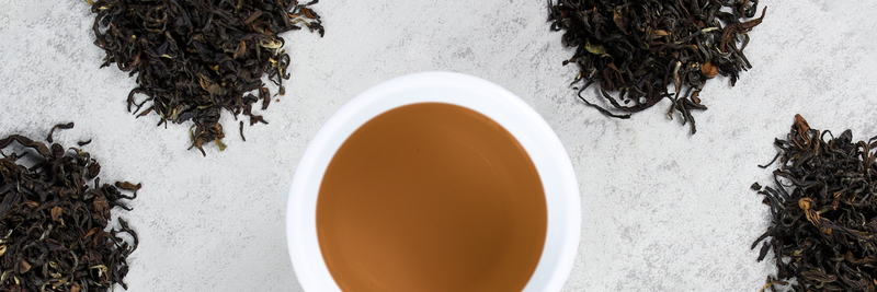 Piles of tea leaves surround a cup of brewed tea