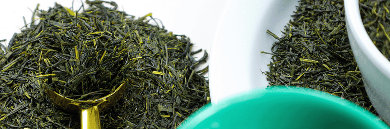 Green Sencha leaves sit on a table.