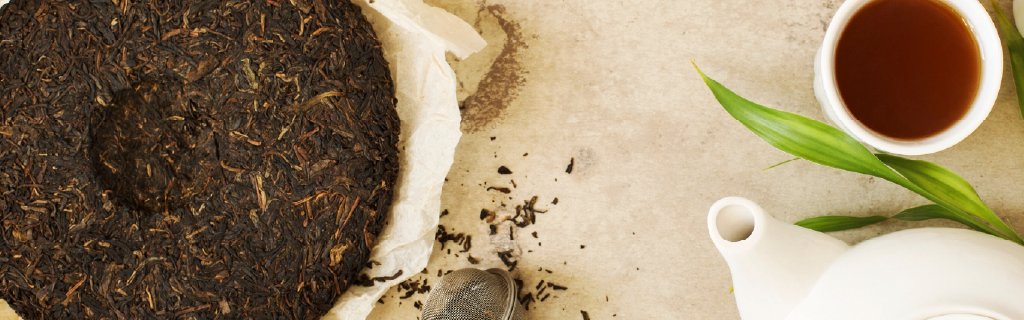 Pu-Erh cake next to a tea pot and tea cup