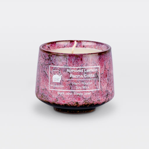A  candle and wick inside a handmade pink and black marbled tea cup, labeled “Almond Lemon Panna Cotta.” "Burn now. Steep later." is the product's tagline