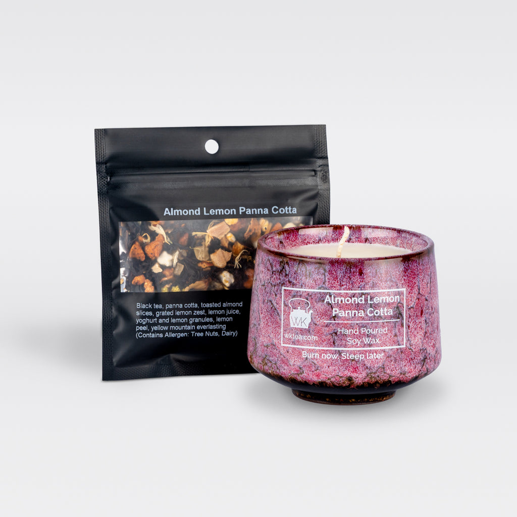 A  pink and black marbled teacup filled with wax and wick is next to a black resealable pouch of loose-leaf tea. Both items are labeled as “Almond Lemon Panna Cotta.”