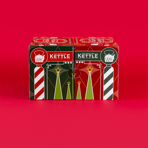 Two festive 12 Days of Tea advent calendar boxes sit side by side against a bright red background with red, green, and white holiday designs