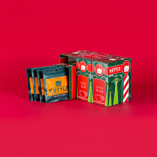 An open 12 Days of Tea advent calendar displays individual tea packets beside the colorful red and green holiday box against a red background