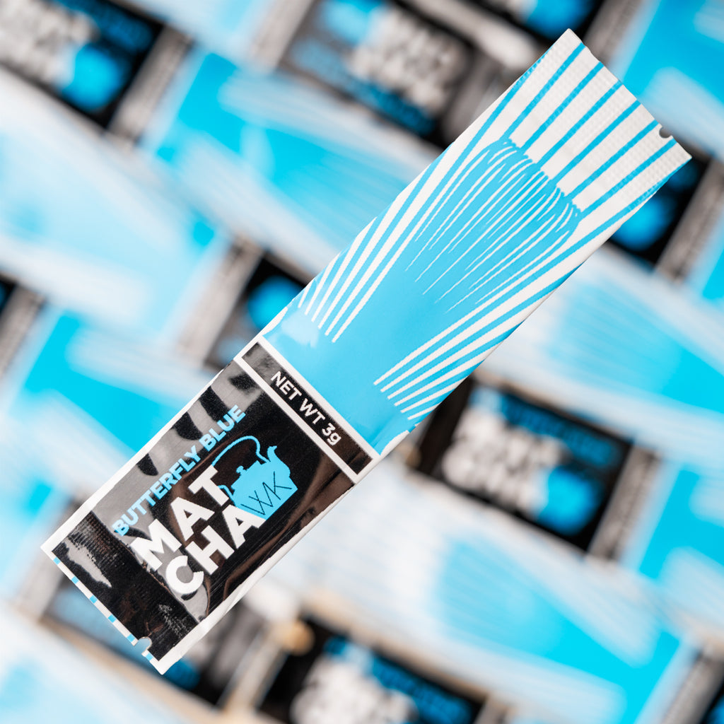 Close-up of a Butterfly Blue Matcha sachet from The Whistling Kettle, shown diagonally against a background of matching light blue and white matcha sachets