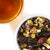Overhead photo of Blackberry Fig tea leas, beside a golden brown brewed cup of tea.