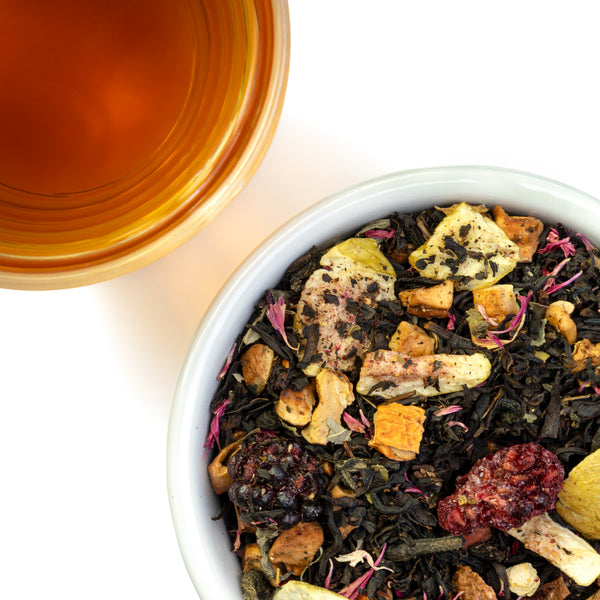 Overhead photo of Blackberry Fig tea leas, beside a golden brown brewed cup of tea.