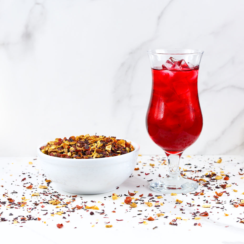 Glass of brewed Blood Orange next to bowl of Blood Orange loose leaf tea.