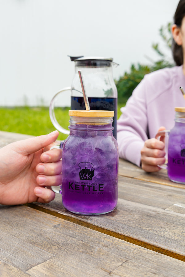 Purple drink in a mason jar with 'Kettle' branding, held by a person outdoors.