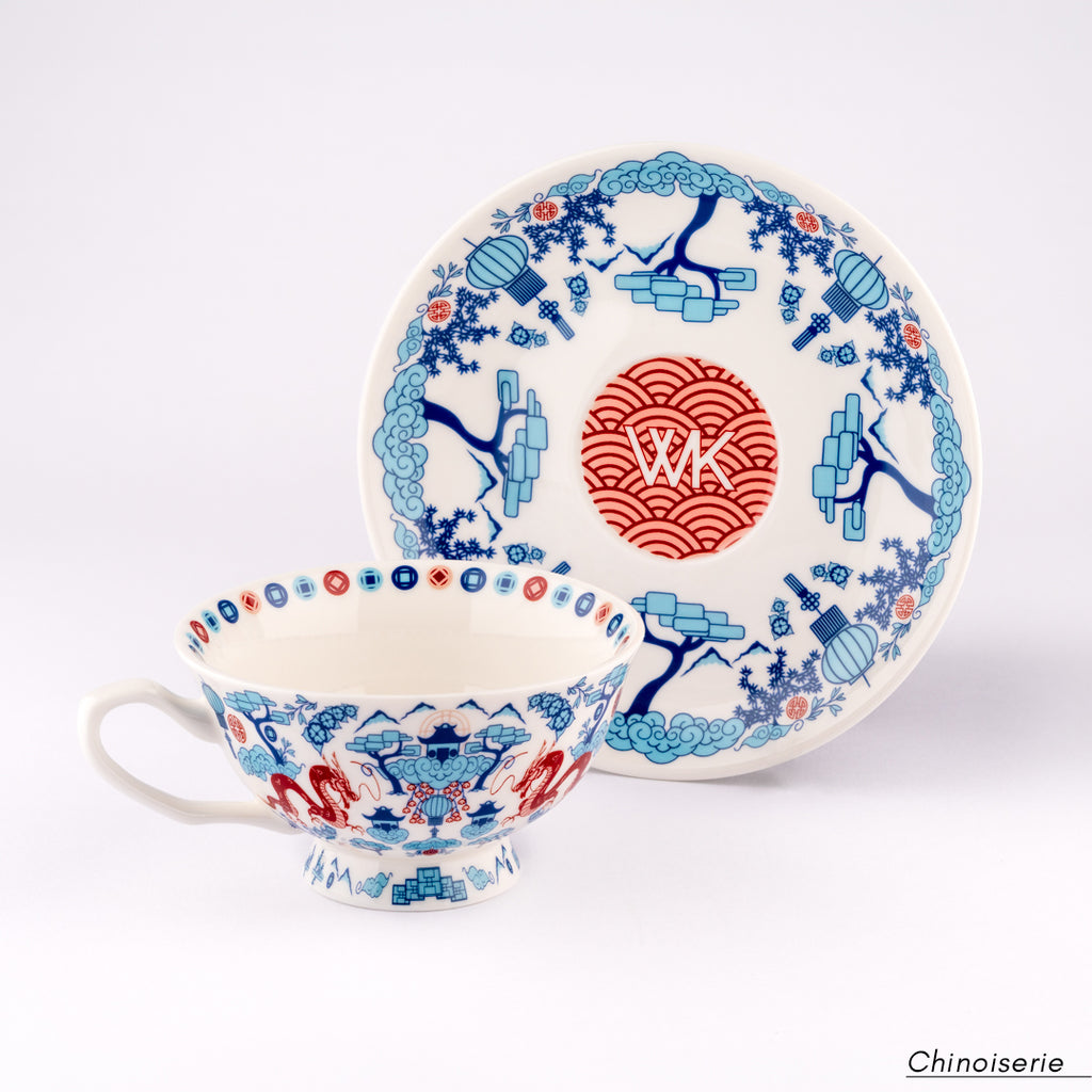 White Chinoiserie ceramic cup and saucer with blue and red decorative patterns and WK logo