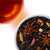 Overhead view of caramel apple chai loose-leaf tea with star anise, cardamom, cinnamon, apple pieces, and warm amber tea