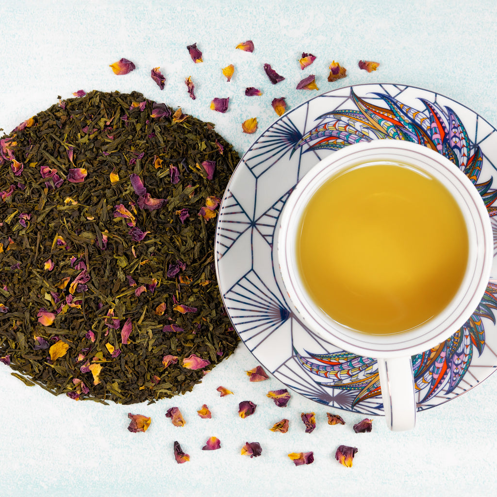 Cup & Saucer of brewed Cherry Rose tea next to mound of Cherry Rose loose leaf tea.