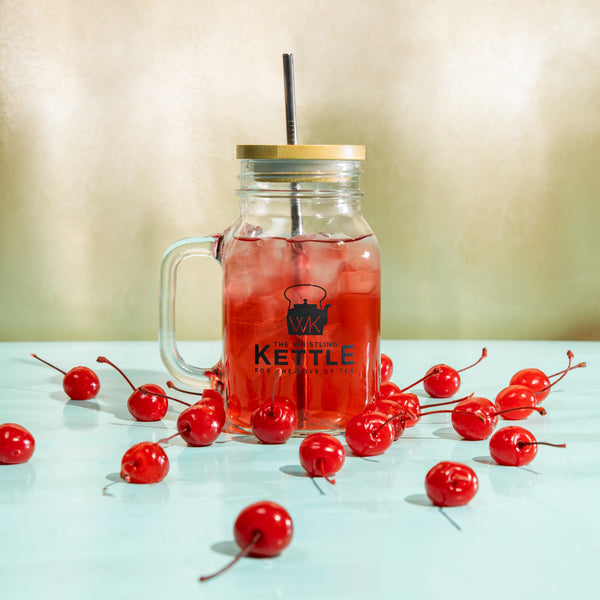 A cherry red glass of cherry bomb fruit iced tea surrounded by cherries