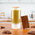 Iced chocolate matcha latte topped with cocoa powder beside dark chocolate bars