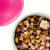 A top-down photo of a cup of bright pink brewed Cotton Candy tea next to a bowl of loose tea.