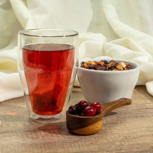 a steeped glass of cranberry vanilla tea next to a pile of cranberries
