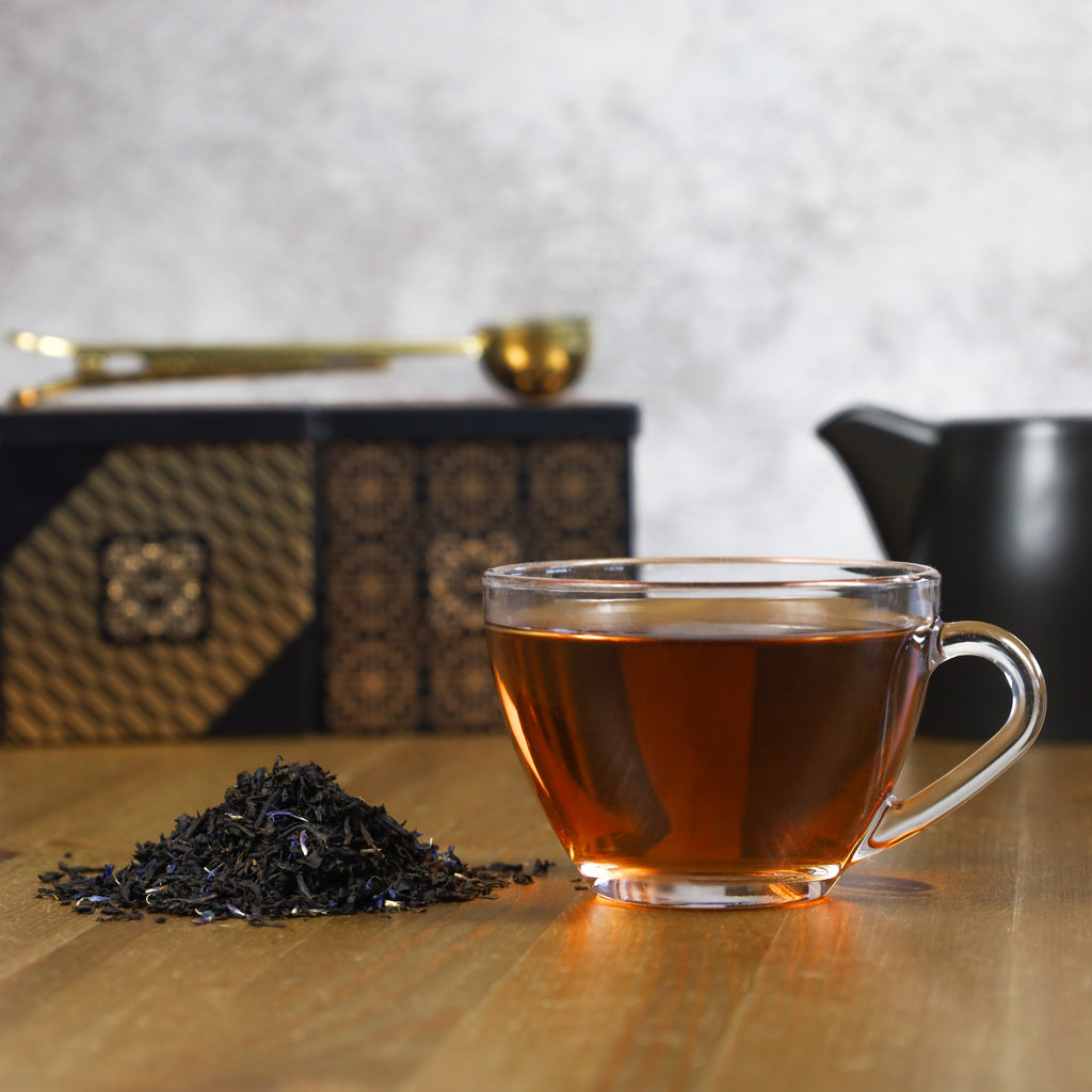 Cup of brewed Earl Grey Cream next to Earl Grey Cream loose leaf tea.