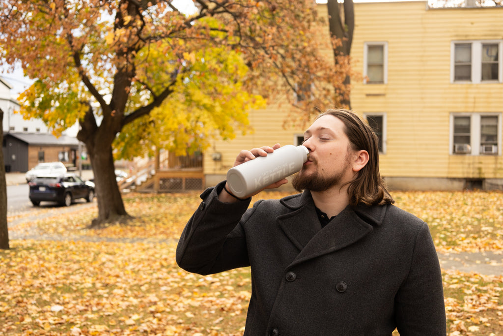 Man sipping out of a tea flask outside in fall weather