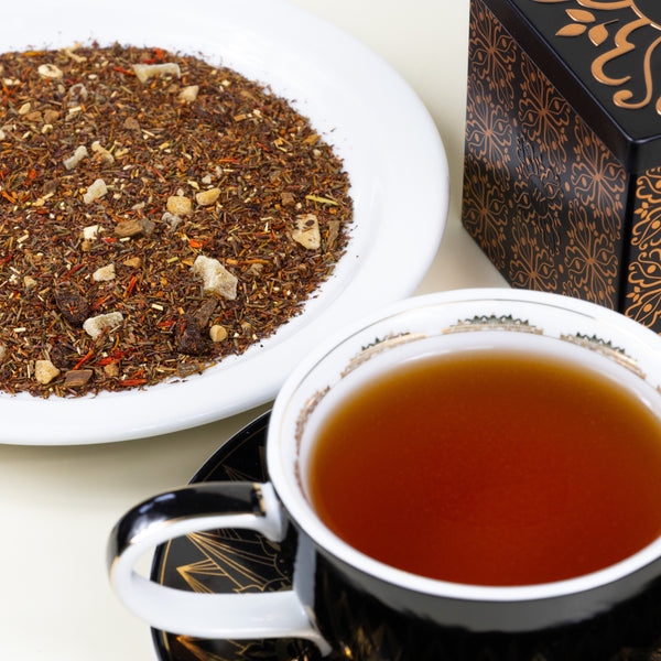 Cup & Saucer filled with brewed Gingerbread Cookie next to Tea Tin and plate of Gingerbread Cookie loose leaf tea.