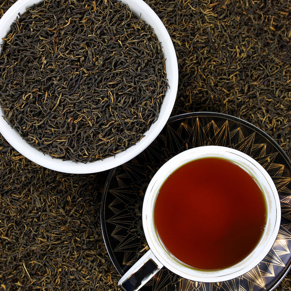 Cup of Golden Monkey tea next to bowl of Golden Monkey tea leaves.