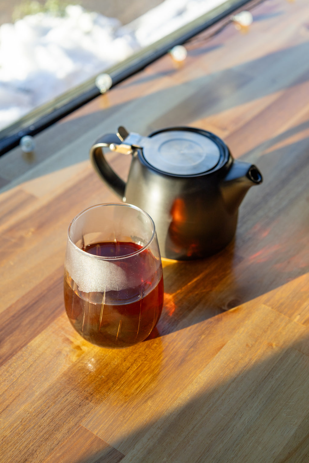 Tea cup and teapot on a wooden table with sunlight casting shadows