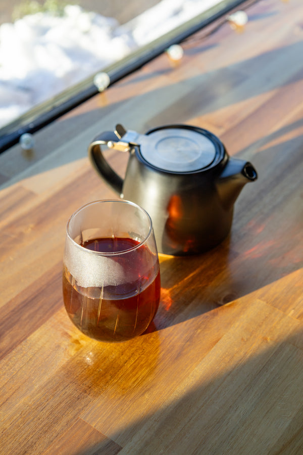 Tea cup and teapot on a wooden table with sunlight casting shadows