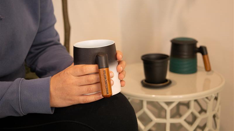Holding a Cream Wave Mug, Teal Wave Mug on table in back
