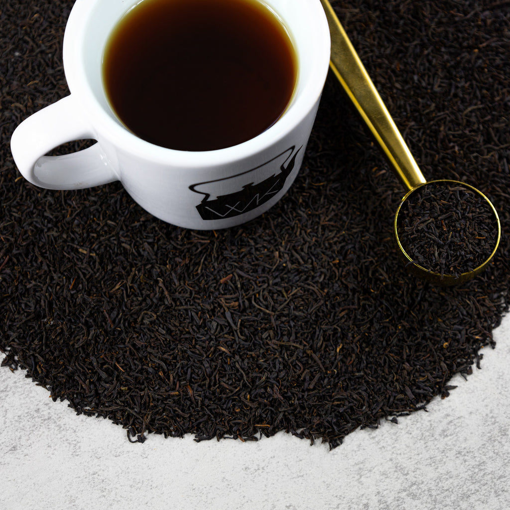 Cup of brewed Keemun Panda tea on top of mound of Keemun Panda loose leaf tea.