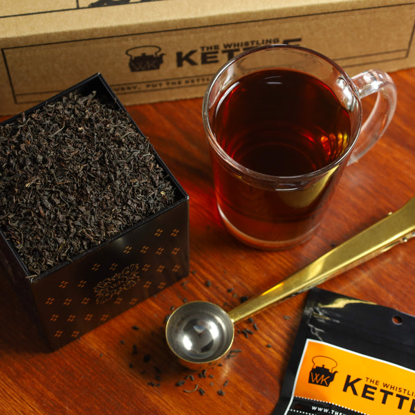 Tea Tin filled with Kettle Iced Tea Blend loose leaf tea next to glass of brewed Kettle Iced Tea Blend.