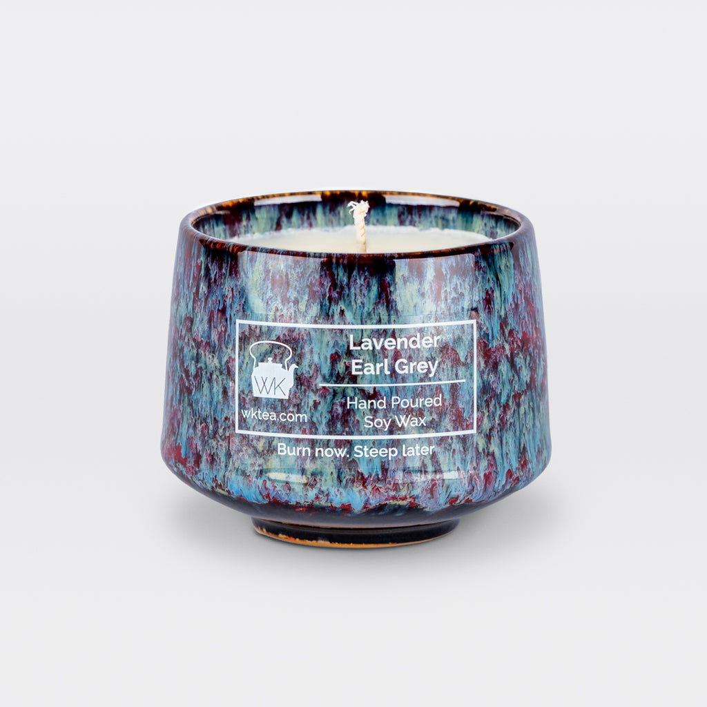 A  candle and wick inside a handmade blue and purple marbled tea cup, labeled “Lavender Earl Grey.” "Burn now. Steep later." is the product's tagline