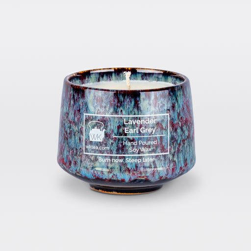 A  candle and wick inside a handmade blue and purple marbled tea cup, labeled “Lavender Earl Grey.” "Burn now. Steep later." is the product's tagline