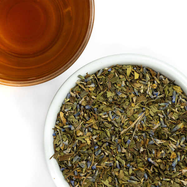 overhead shot of a bowl full of lavender mint tea next to a steeped cup