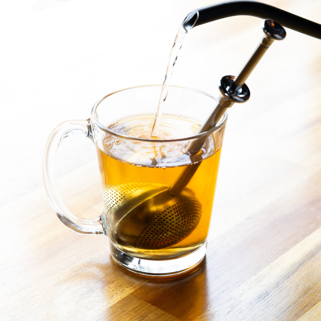 The Whistling Kettle Lil' Springer Long Handle Tea Ball Infuser in cup.