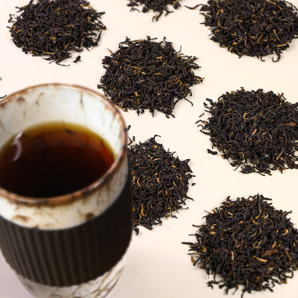 Ceramic Bird's Egg Travel Mug filled with Mokalbari East Assam next to mounds of Mokalbari East Assam loose leaf tea.