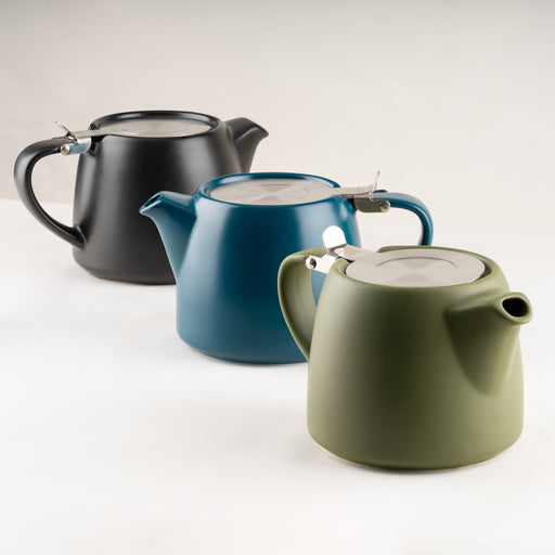 Three ceramic teapots in black, blue, and green on a white background.