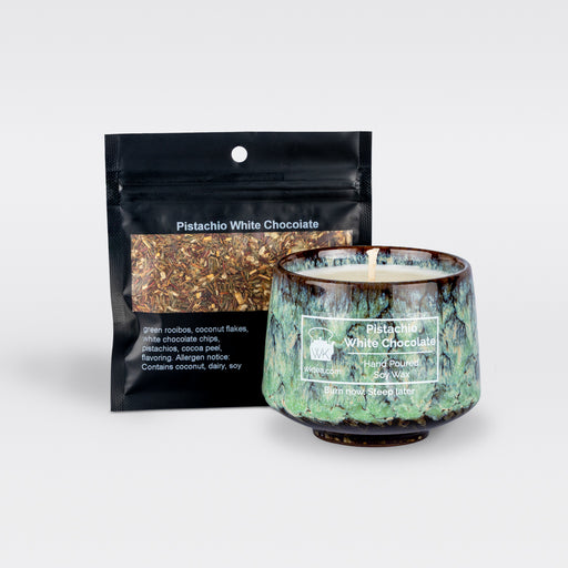 A  green and brown marbled teacup filled with wax and wick is next to a black resealable pouch of loose-leaf tea. Both items are labeled as “Pistachio White Chocolate.”